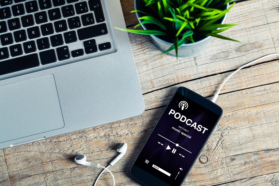 Mobile phone placed on a wooden desk with podcast app in the screen.